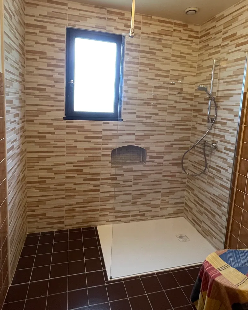 Après : grande douche avec paroi vitrée et faïence neuve